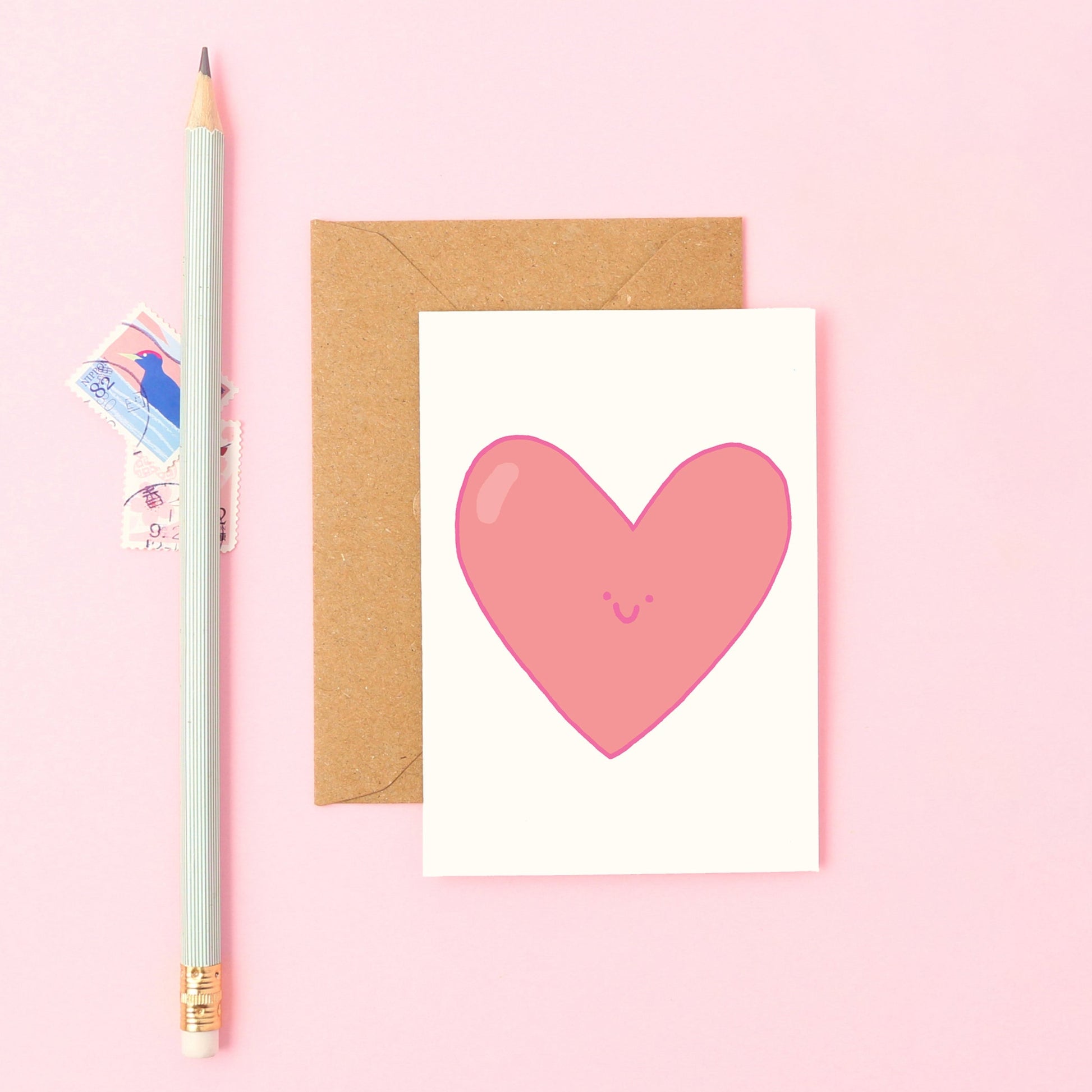 cute Mini heart greeting card with smiling pink heart design and kraft envelope.