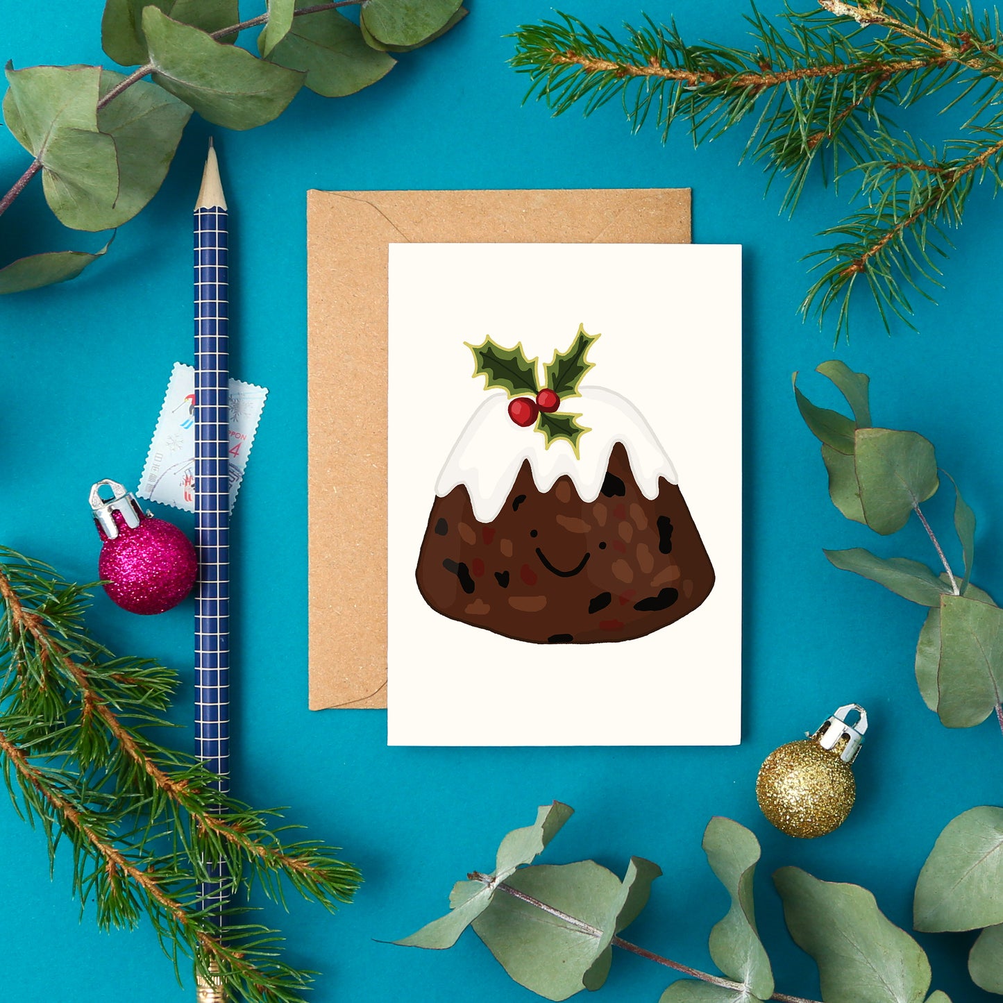A jolly mini greeting card with a festive hand-drawn Christmas pudding topped with holly and a cute smile.