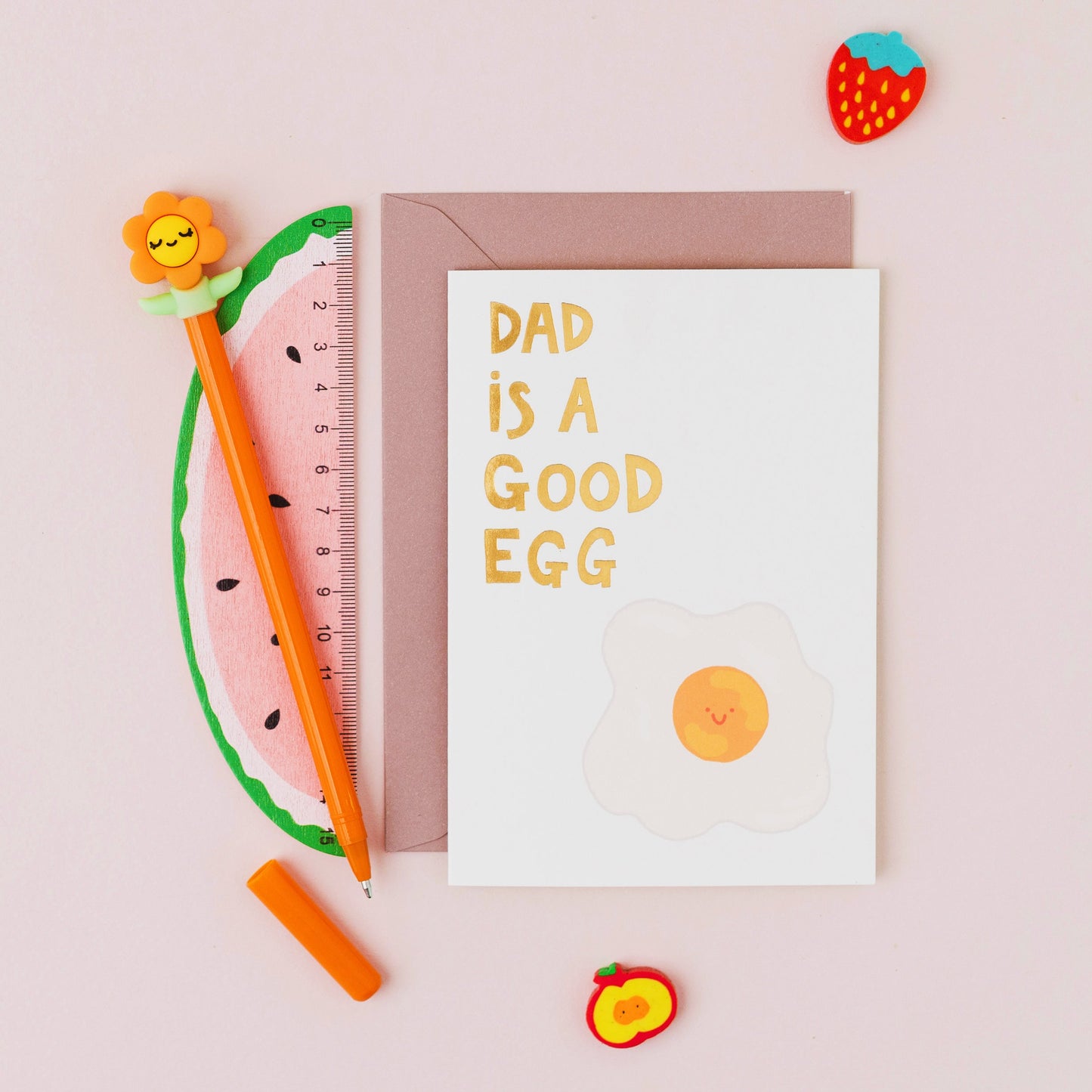 Dad Is A Good Egg Father's Day card featuring a smiling fried egg with gold foil lettering on a contemporary white background.