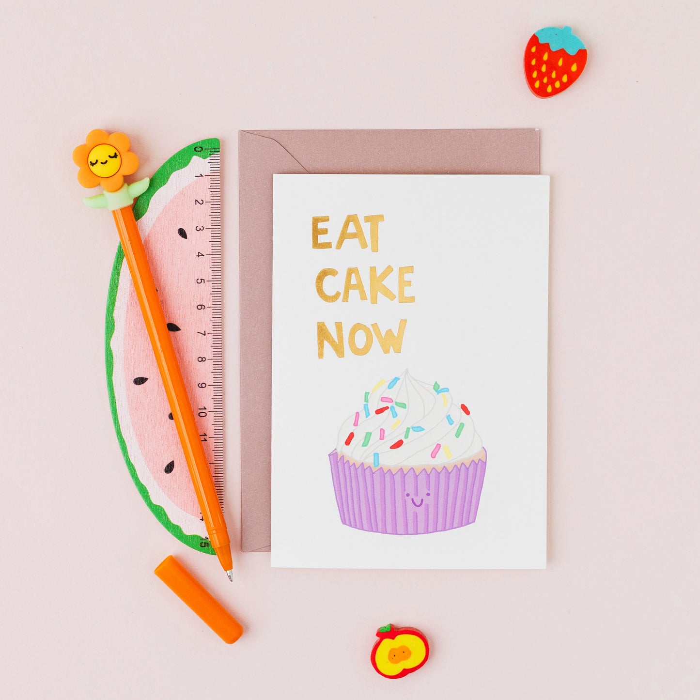 Eat Cake Now greeting card featuring a smiling cupcake with gold foil lettering on a contemporary white background.