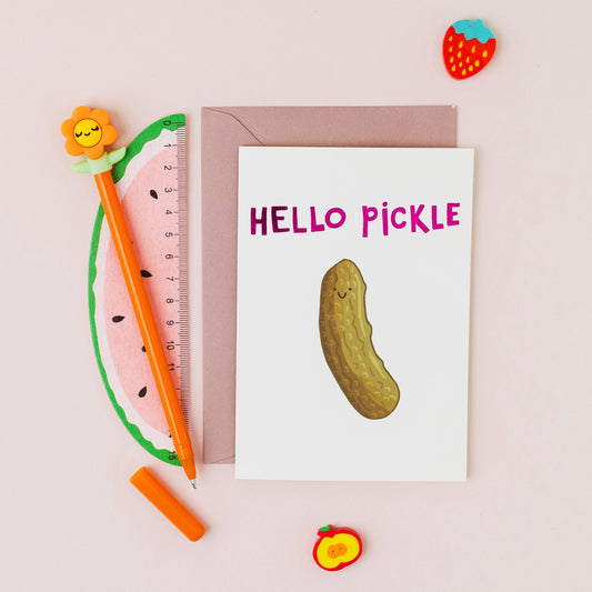 Hello Pickle greeting card featuring a smiling pickle with pink foil lettering on a contemporary white background.