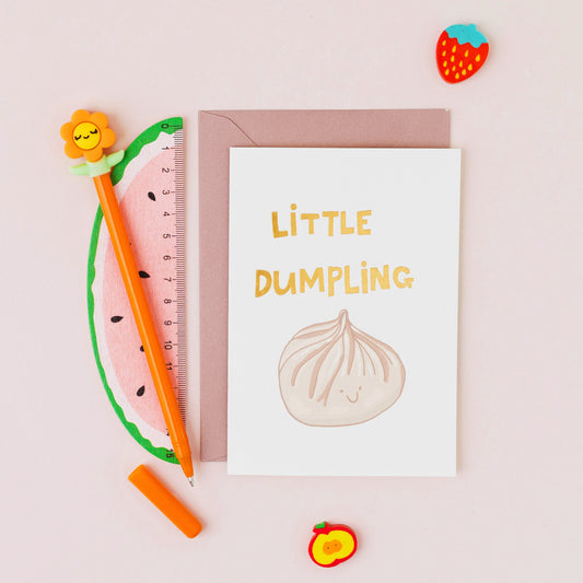 Little Dumpling greeting card featuring a smiling steamed dumpling with gold foil lettering on a contemporary white background.