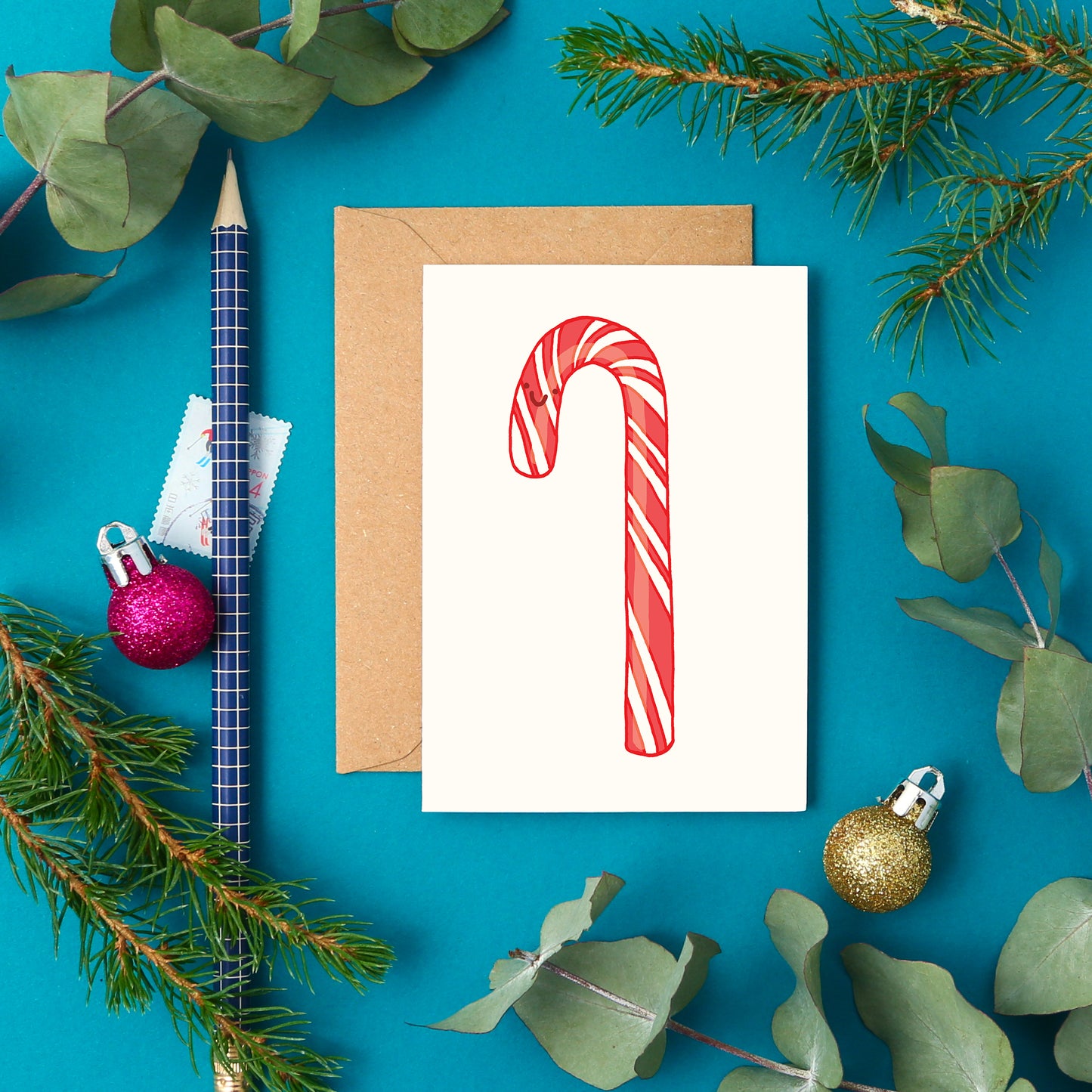 Cute mini festive greeting card with a red and white striped candy cane and smiley face.