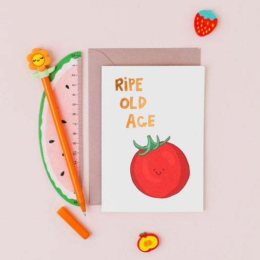 Ripe Old Age birthday card featuring a smiling tomato with gold foil lettering on a contemporary white background.