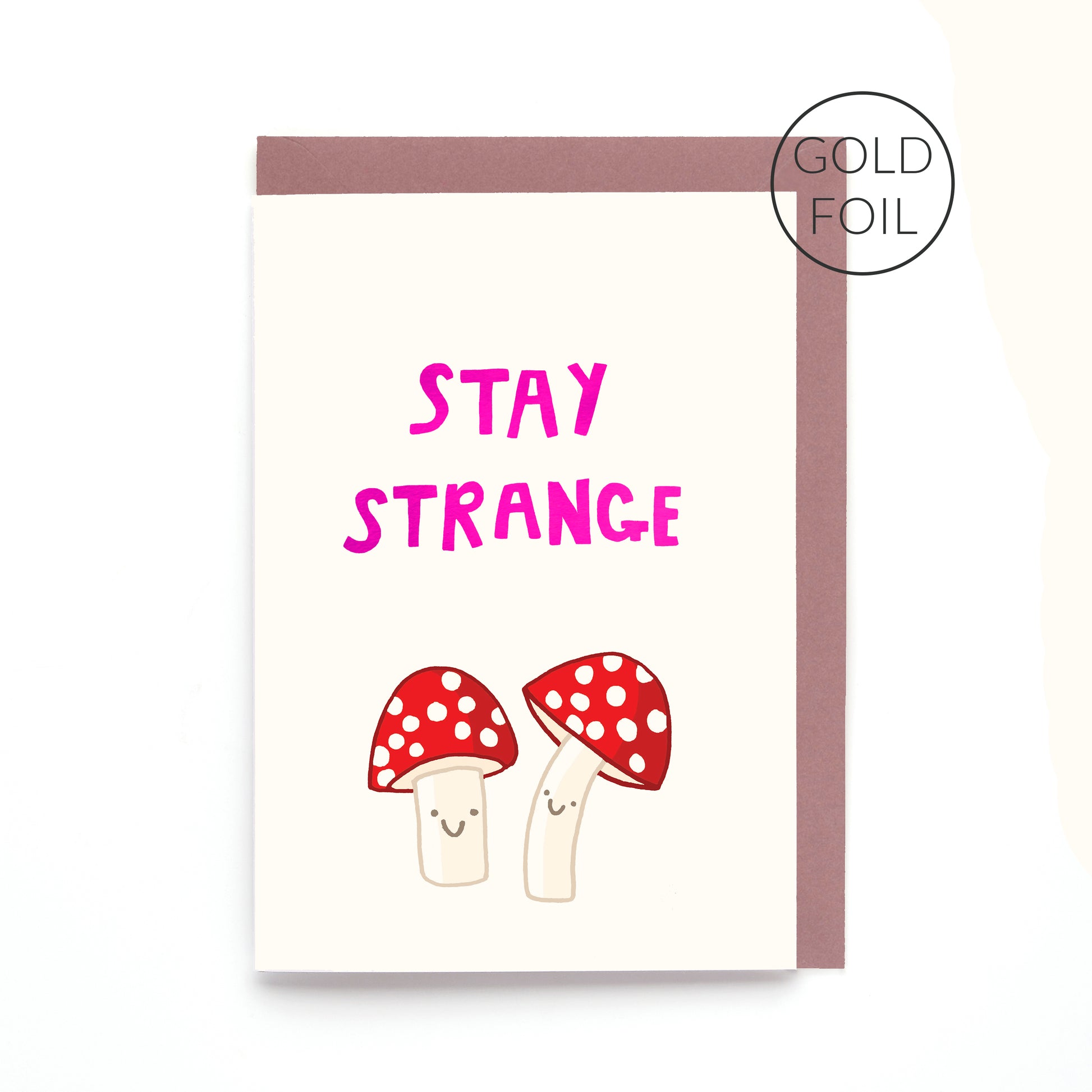 Hand drawn fly agaric mushroom greeting card reading "Stay Strange" with gold foil lettering on a white background.