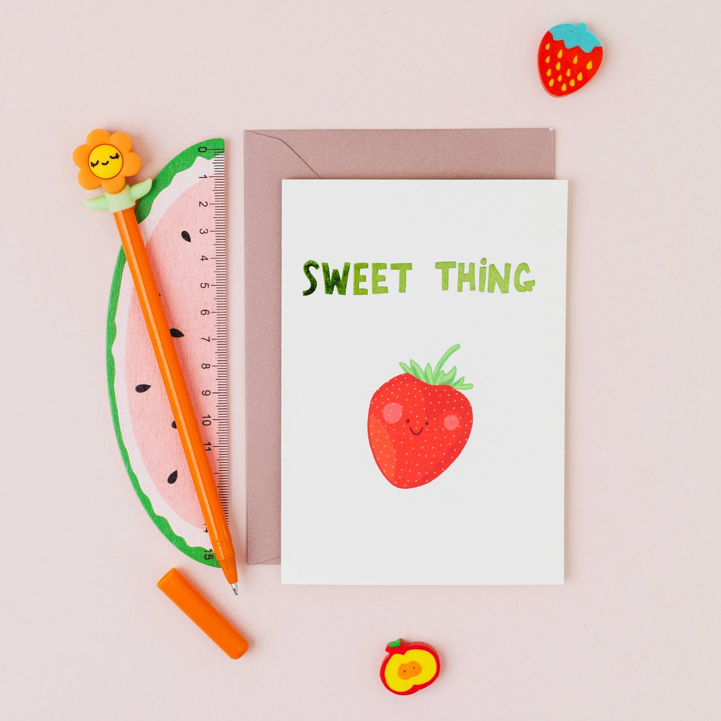 Hand drawn smiling strawberry greeting card with the words 'Sweet Thing' in green hot foil on a white background.