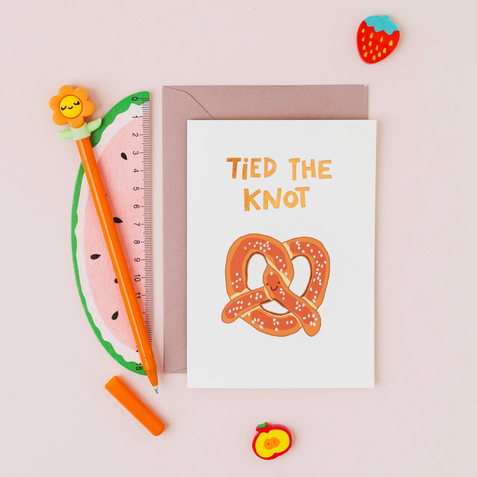 Hand drawn pretzel wedding greeting card with the words 'Tied The Knot' in gold foil on a white background.
