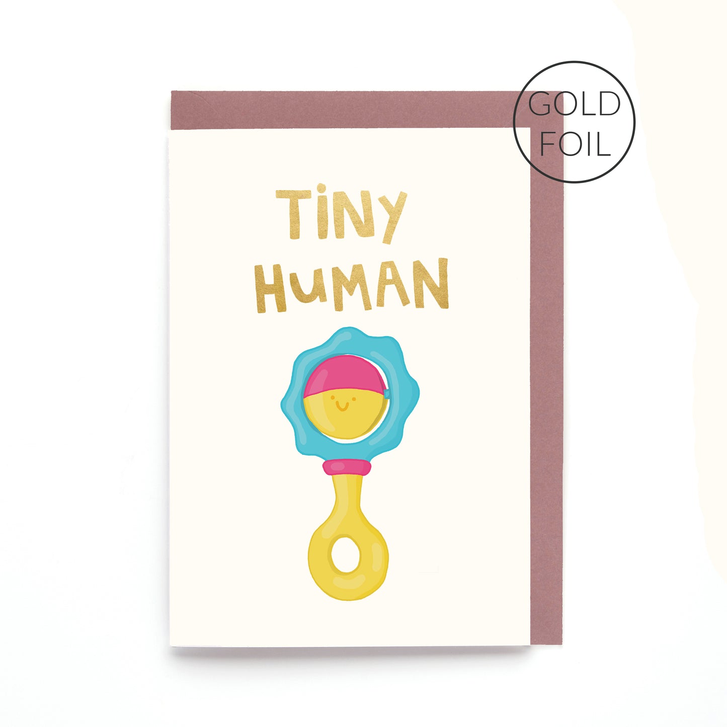 Hand drawn smiling baby rattle greeting card with the words 'Tiny Human' in gold foil on a white background.